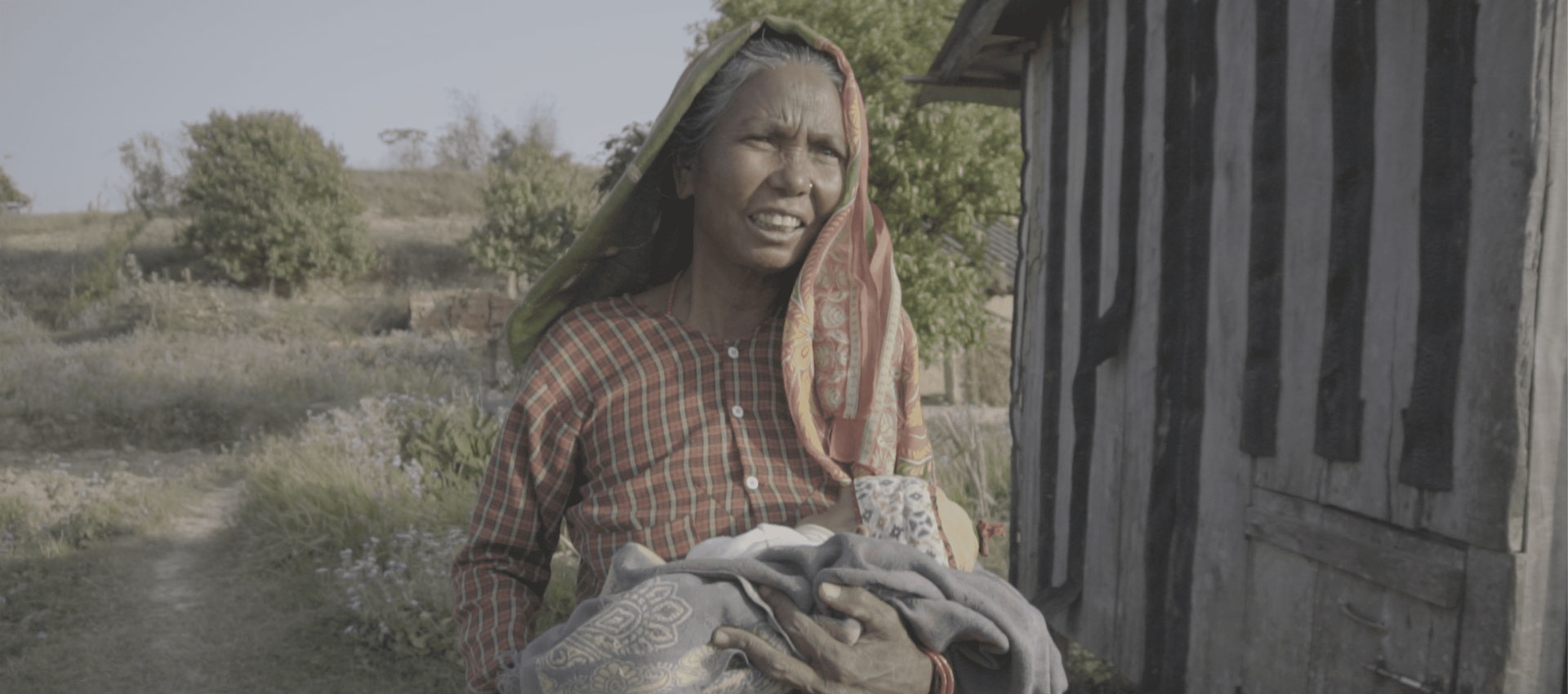 Woman walking forward holding bundled baby